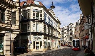 Blick auf das moderne Gebäude der Deutschen Bank an einer Fußgängerzone in Halle mit Passanten und umliegenden historischen Gebäuden