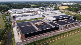 Luftaufnahme der Produktionshalle mit Ansicht der Solarkollektoren an den Wänden des Gebäude.