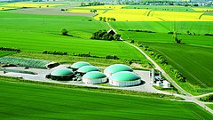 Luftaufnahme eines grünen Feldes mit sechs grünen Kuppeln der Biomethananlage Willingshausen