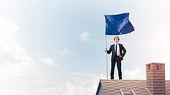 Mann in Anzug mit blauer Fahne auf dem Dach.