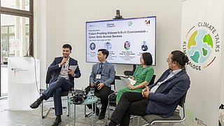 Vier Personen sitzen vor einem großen Bildschirm, dort ist zu lesen: "Future-Proofing Vietnam's Build Environment - Greven Skills Across Sektors". Sie diskurtieren. Die Teilnehmer von links nach rechts: Tun Ngo, Seniorexperte der Deutschen Energieagentur (dena), Assoc. Prof. Dr. Nguyen Vu Phuong, Vice President, Academy of Construction Strategy and Cadres Training, Ministry of Construction, Associate Prof. Dr. Dang Thi Thanh Huyen, Vice Dean, Faculty of International Education, Hanoi University of Civil Engineering, Mr. Tran Cong Duc, Chief Representative Vietnam, gmp Architects