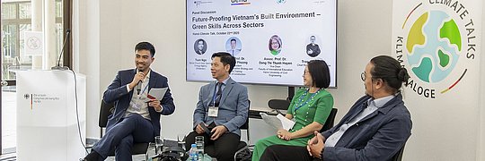 Vier Personen sitzen vor einem großen Bildschirm, dort ist zu lesen: "Future-Proofing Vietnam's Build Environment - Greven Skills Across Sektors". Sie diskurtieren. Die Teilnehmer von links nach rechts: Tun Ngo, Seniorexperte der Deutschen Energieagentur (dena), Assoc. Prof. Dr. Nguyen Vu Phuong, Vice President, Academy of Construction Strategy and Cadres Training, Ministry of Construction, Associate Prof. Dr. Dang Thi Thanh Huyen, Vice Dean, Faculty of International Education, Hanoi University of Civil Engineering, Mr. Tran Cong Duc, Chief Representative Vietnam, gmp Architects