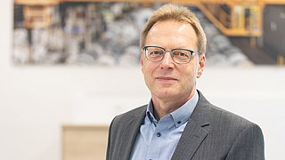 Ralf Schaper, Leiter Energiewirtschaft bei Salzgitter, sitzend auf einem Tisch.