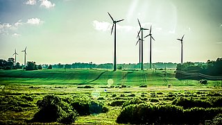 Windkraftanlagen auf einem grünen Feld unter bewölktem Himmel