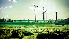 Windkraftanlagen auf einem grünen Feld unter bewölktem Himmel