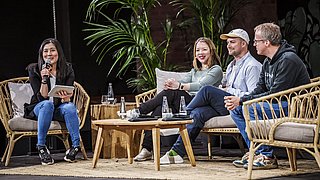 Vier Personen sitzen auf einer Bühne und diskutieren miteinander.