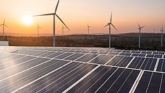 Solar panels and wind generators under blue sky on sunset