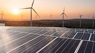 Solar panels and wind generators under blue sky on sunset