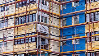 Fassade eines mehrstöckigen Gebäudes mit Gerüst und teilweise isolierter Außenwand