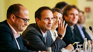 Mehrere Personen sitzen an einem Tisch, in der Mitte spricht Christian Stolte, Bereichsleiter Klimaneutrale Gebäude Prokurist, gestikulierend ins Mikrofon.