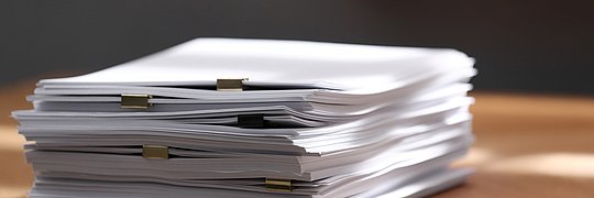 Stapel unbeschriebenes Papier mit Heftklammern auf einem Holztisch in einem Innenraum
