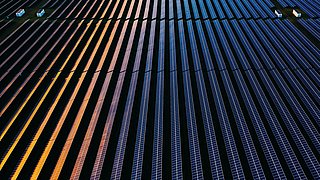 Drone view over a field of solar panels at sunset
