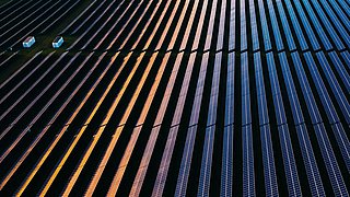 Drone view over a field of solar panels at sunset