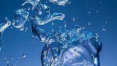 Wasserblasen und -tröpfchen in verschiedenen Formen und Größen, die in einer blauen Umgebung schweben.