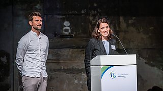 Eine Frau hält eine Rede auf der Bühne.