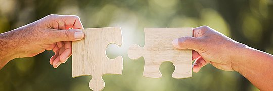 Zwei Händen mit zwei Puzzleteilen