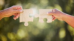 Zwei Händen mit zwei Puzzleteilen