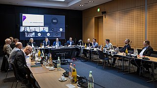 Austausch von Mitgliedern in Konferenzraum mit Mikros