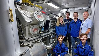 Mitarbeiter der SCHOTT AG vor einer Wärmepumpe.