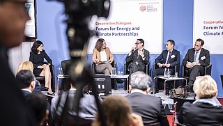 Podiumsdiskussion zum Thema Energie- und Klimapartnerschaften beim Berlin Energy Transition Dialogue 2024. Fünf Personen sitzen auf der Bühne, eine spricht ins Mikrofon. Publikum im Vordergrund, Kamera teilweise im Bild.