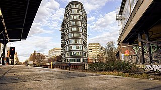 Moderner EUREF-Gebäudekomplex neben einer Bahnstrecke mit Graffiti an den Wänden.