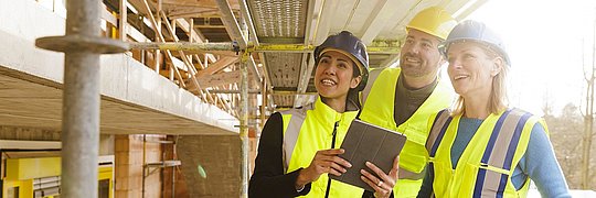 Zwei Energieeffizienzberaterinnen und ein Energieeffizienzberater im Gespräch auf einer Baustelle