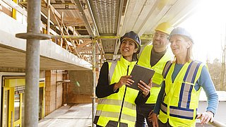 Zwei Energieeffizienzberaterinnen und ein Energieeffizienzberater im Gespräch auf einer Baustelle