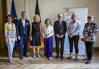 Gruppenshot von sieben Personen in formeller Kleidung, stehend vor einem Banner mit dem Logo der Deutschen Energie-Agentur und Flaggen von Polen und Deutschland.