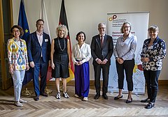 Gruppenshot von sieben Personen in formeller Kleidung, stehend vor einem Banner mit dem Logo der Deutschen Energie-Agentur und Flaggen von Polen und Deutschland.