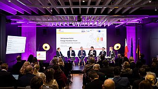 Podiumsdiskussion mit sechs Personen vor Publikum in einem Raum mit lila Beleuchtung und einer Präsentation zum 3rd German-Polish Energy Transition Forum