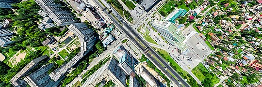 Luftaufnahme einer Stadt mit hohen Wohngebäuden, breiten Straßen und grünen Flächen.