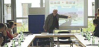 Ein Referent erläutert bei seinem Vortrag eine PowerPoint-Folie.