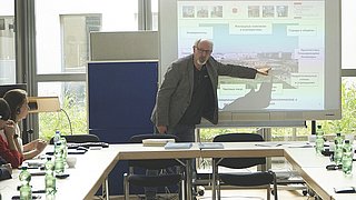 Ein Referent erläutert bei seinem Vortrag eine PowerPoint-Folie.