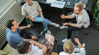 5 Personen des SET Mentoring Programms von oben fotografiert wie sie in einem Kreis zusammensitzen und miteinander sprechen