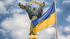 Statue von Berehynia auf dem Unabhängigkeitsplatz in Kiew, Ukraine, davor die ukrainische Flagge