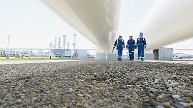 Arbeiter laufen unter den Tankanlagen einer Gasfabrik.