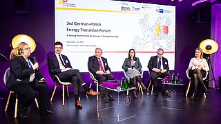 Sechs Personen sitzen auf einer Bühne vor einem Bildschirm mit dem Text '3rd German-Polish Energy Transition Forum' und diskutieren in einem Forum mit lila Beleuchtung