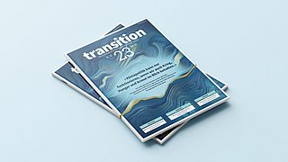 Zwei Stapel Zeitschriften mit dem Titel 'transition 23'. Die Cover zeigen eine abstrakte, wellenförmige Musterung in Blau- und Grüntönen.