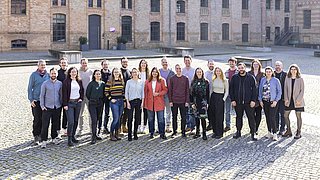 Eine große Gruppe von dena-Mitarbeitenden stehen im Hof des Standorts vom Future Energy Lab