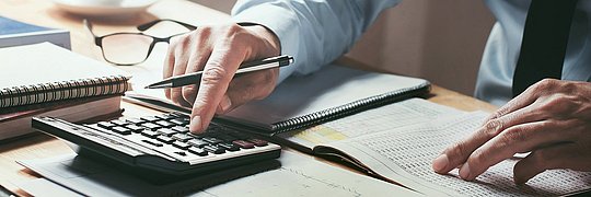 Geschäftsperson gibt Zahlen in einen Taschenrechner ein.