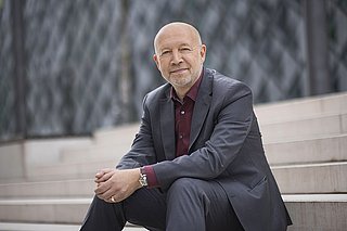 Porträt von Andreas Kuhlmann, der auf einer Treppe sitzt