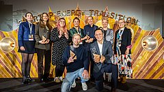 Gruppe von neun Personen mit Auszeichnungen posiert vor einer goldfarbenen Wand mit dem Schriftzug 'STARTUP ENERGY TRANSITION'.