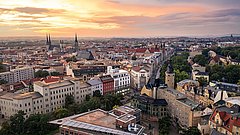 Stadtpanorama von Halle (Saale) bei Sonnenuntergang mit historischen Gebäuden, Kirchtürmen und dicht bebauten Straßen.
