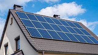 Hausdach mit mehreren Solarpaneelen unter blauem Himmel