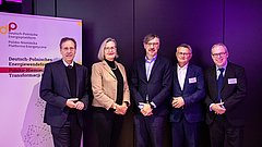 Fünf Personen in formeller Kleidung stehen vor einem Banner der Deutsch-Polnischen Energieplattform in einem Raum mit lila Hintergrundbeleuchtung