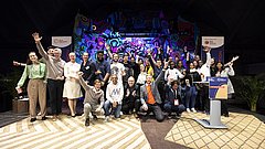 Gruppenfoto der Gewinner des SET Award 2023 auf Bühne mit buntem Hintergrund, einige Personen jubeln mit erhobenen Armen