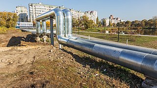 Moderne Hochwärmerohre, die Wärme zur Beheizung der Stadt leiten vor einem Wohnviertel. Offene Verlegung auf Pfeilern. 