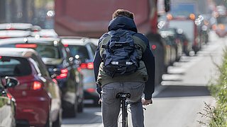 Person auf Fahrrad fährt an einem Autostau vorbei