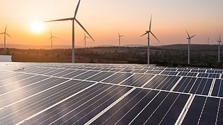 Solar panels and wind generators under blue sky on sunset