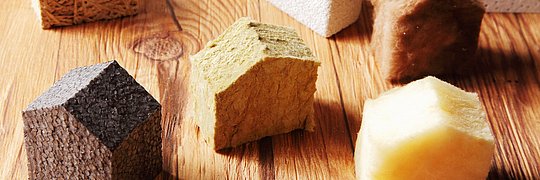 Nahaufnahme verschiedener geschliffener Isolierblöcke in Häuserform auf einem Holztisch.